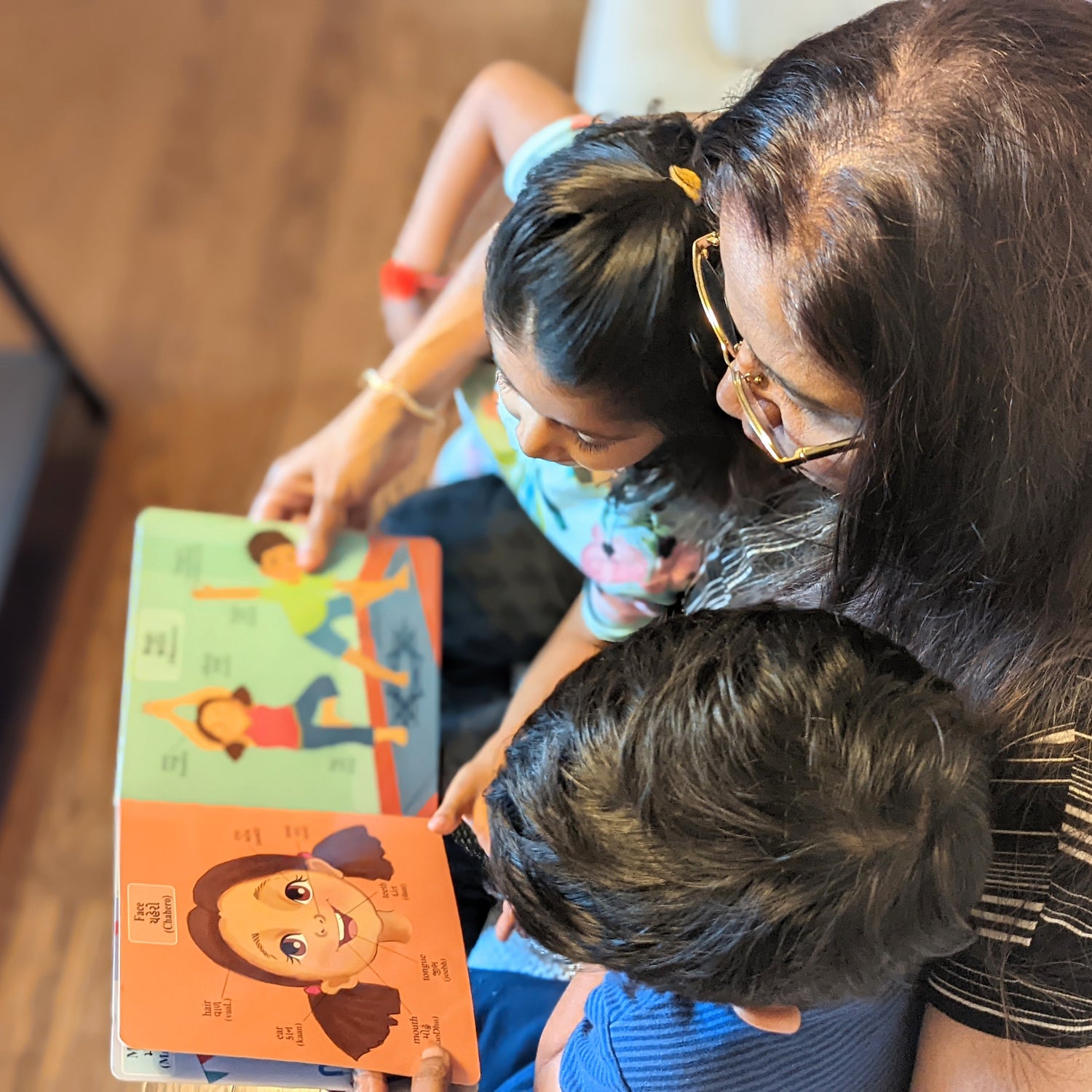Indian-grandma-reading-gujarati-english-bilingual-first-words-book-with-her-grandchildren